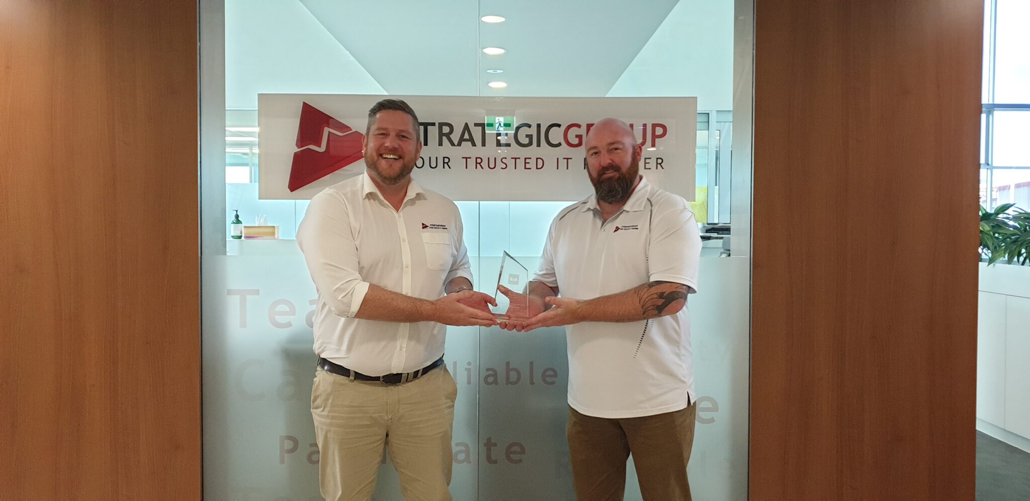 Strategic Group’s Director of Business Development, Aron Robertson with the General Manager of Telecommunications, Adam Fairless, holding their 8x8 Annual Partner Award (left-right).